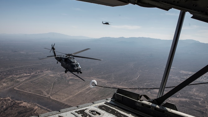 A photo of a helicopter performing air-to-air refueling