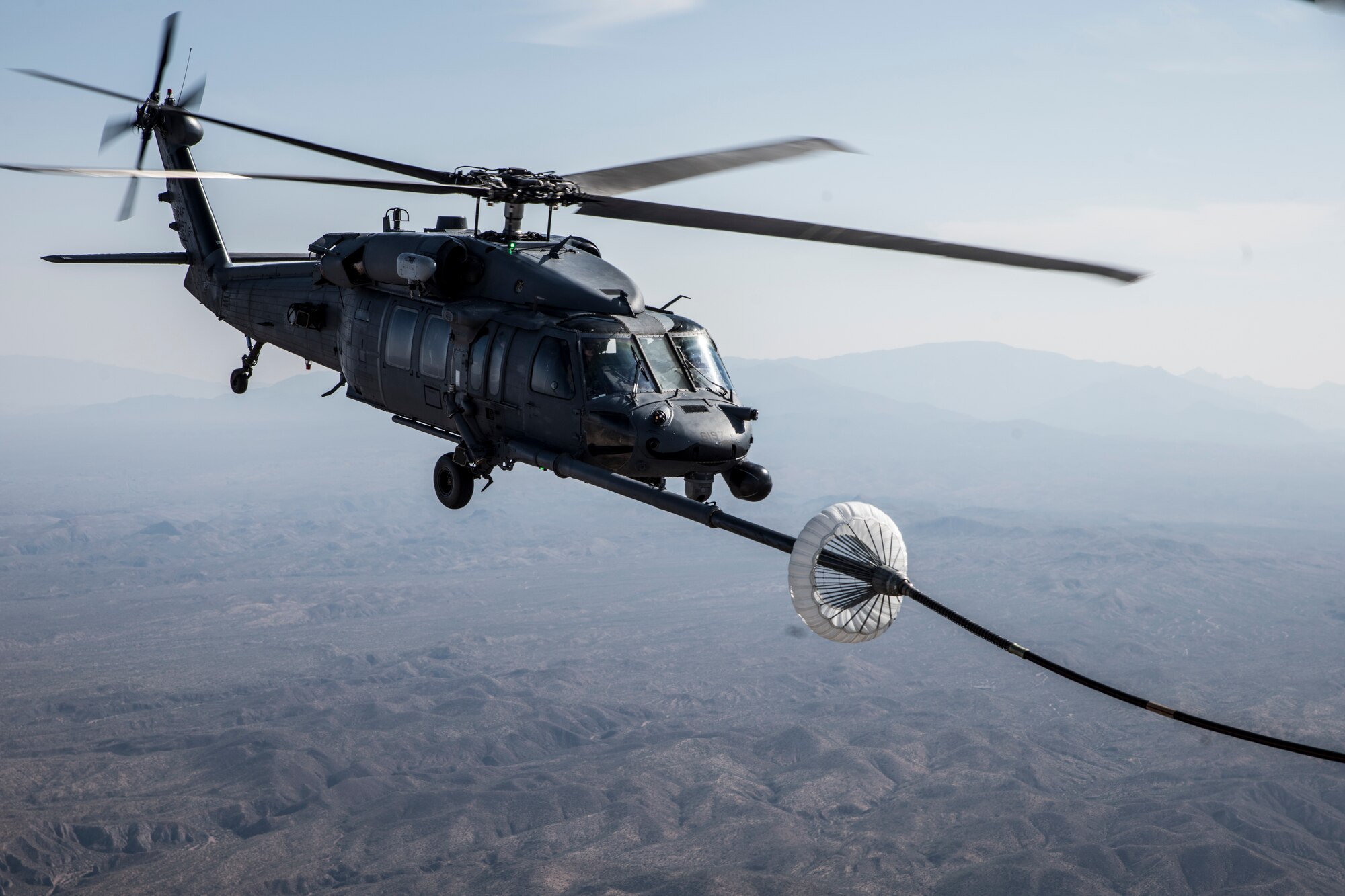 A photo of a helicopter performing air-to-air refueling