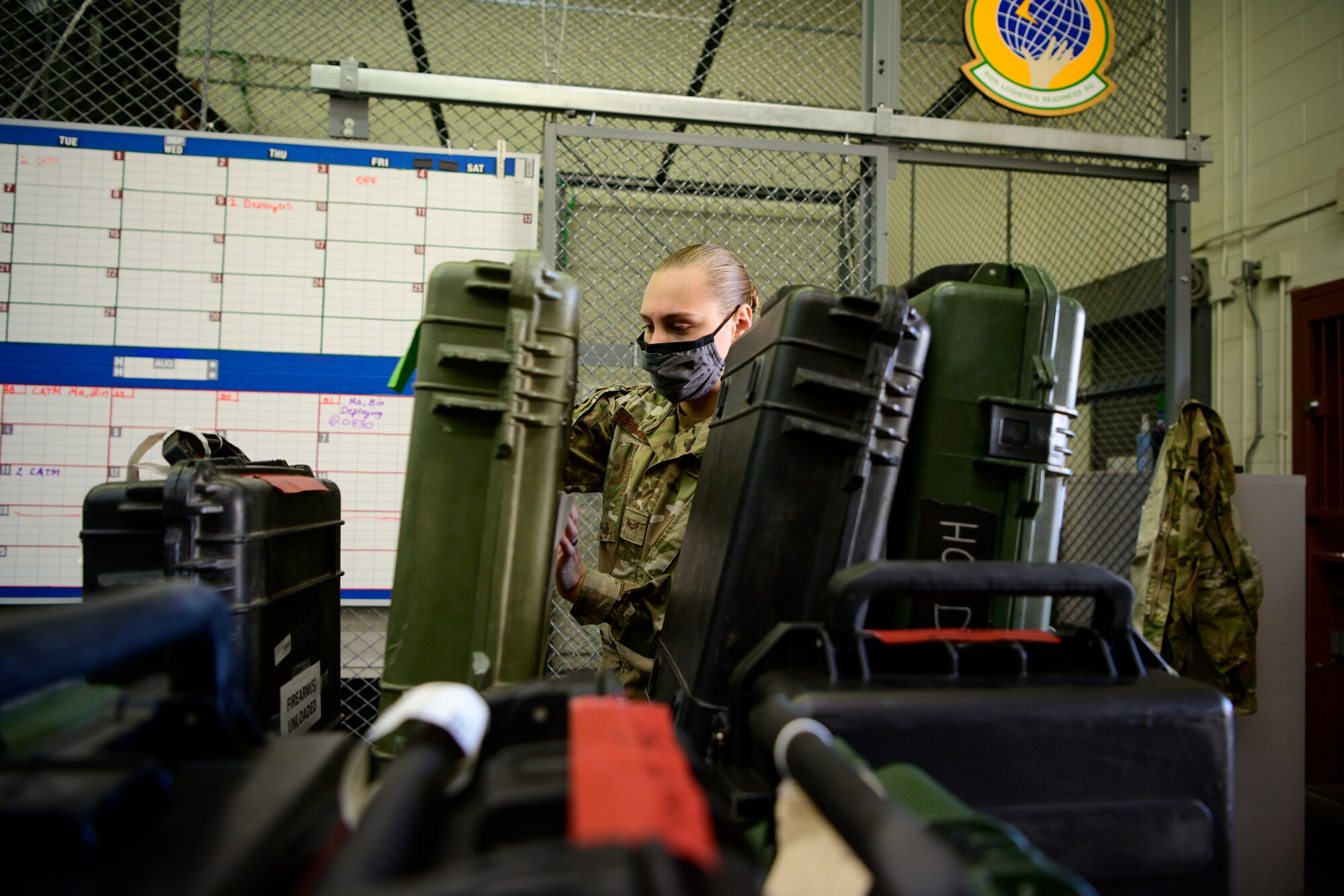 A female Airman moves weapons cases inside an armory.