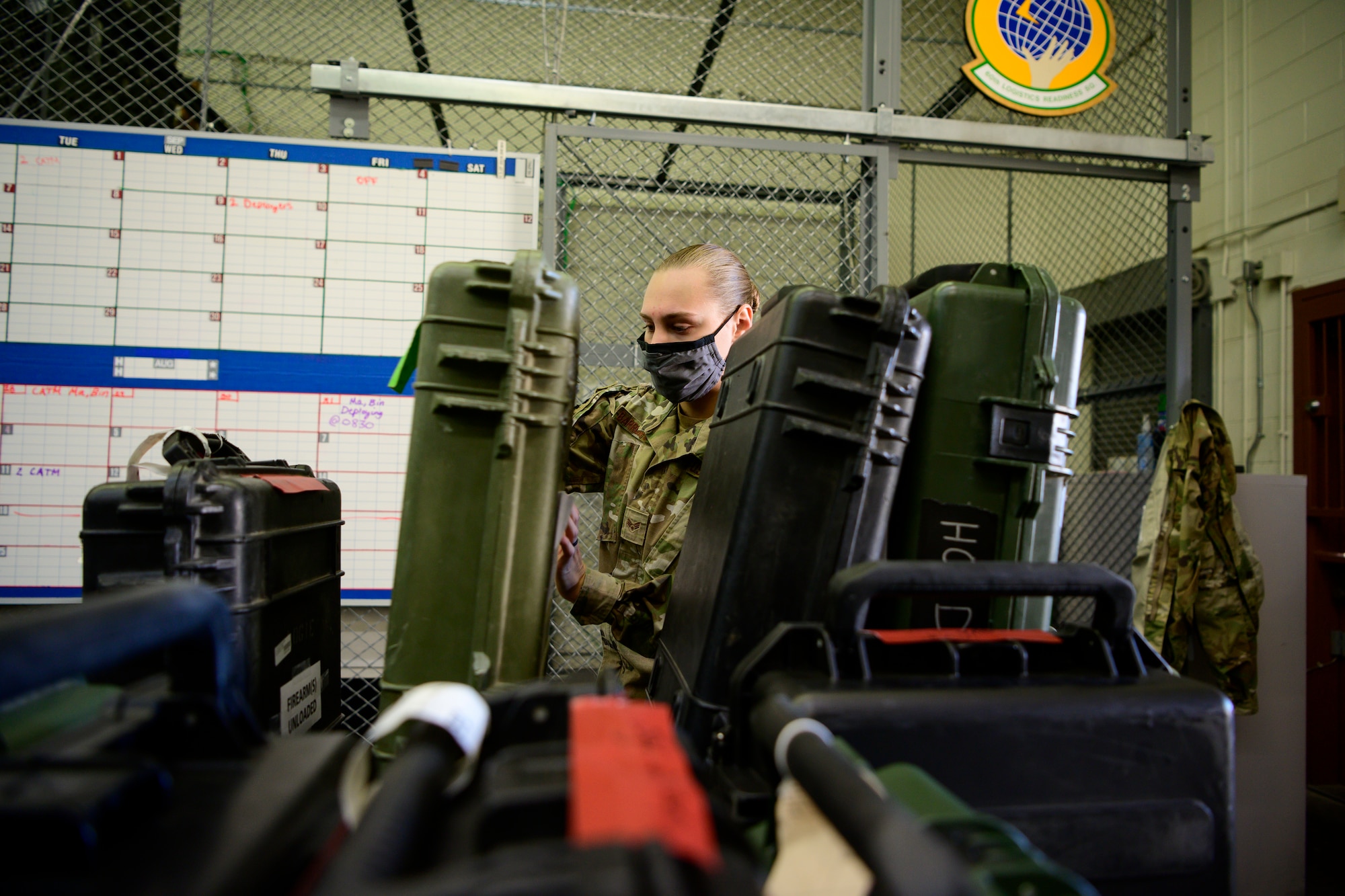 A female Airman moves weapons cases inside an armory.