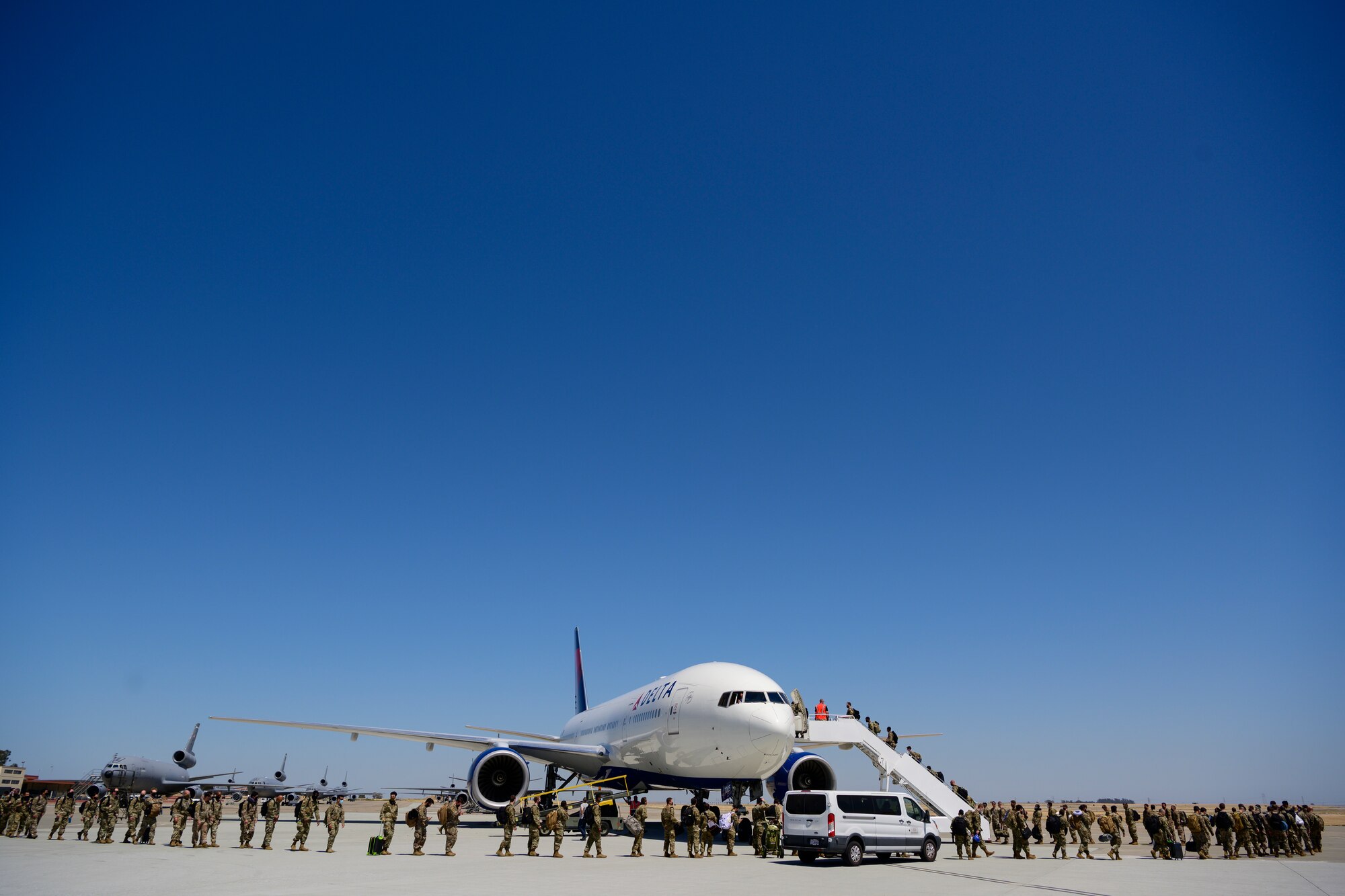 A very long line of Airmen proceed on the flight line to a large white commercial jet.