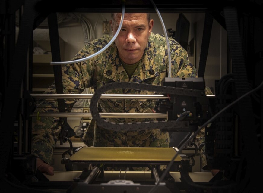 PHILIPPINE SEA (Aug. 24, 2020) Staff Sgt. Jack Hubbard, a radio technician with Combat Logistics Battalion 31, 31st Marine Expeditionary Unit (MEU), observes a 3D printer as it prints an equipment part used aboard USS New Orleans (LPD 18).
