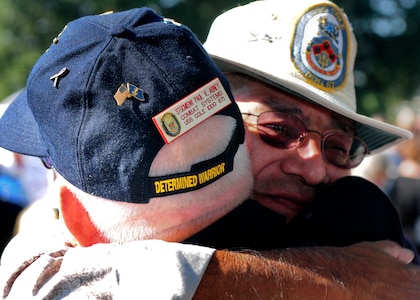 Former crew members of the guided-missile destroyer USS Cole embrace before the beginning of the tenth anniversary remembrance ceremony of the terrorist attack on Cole.