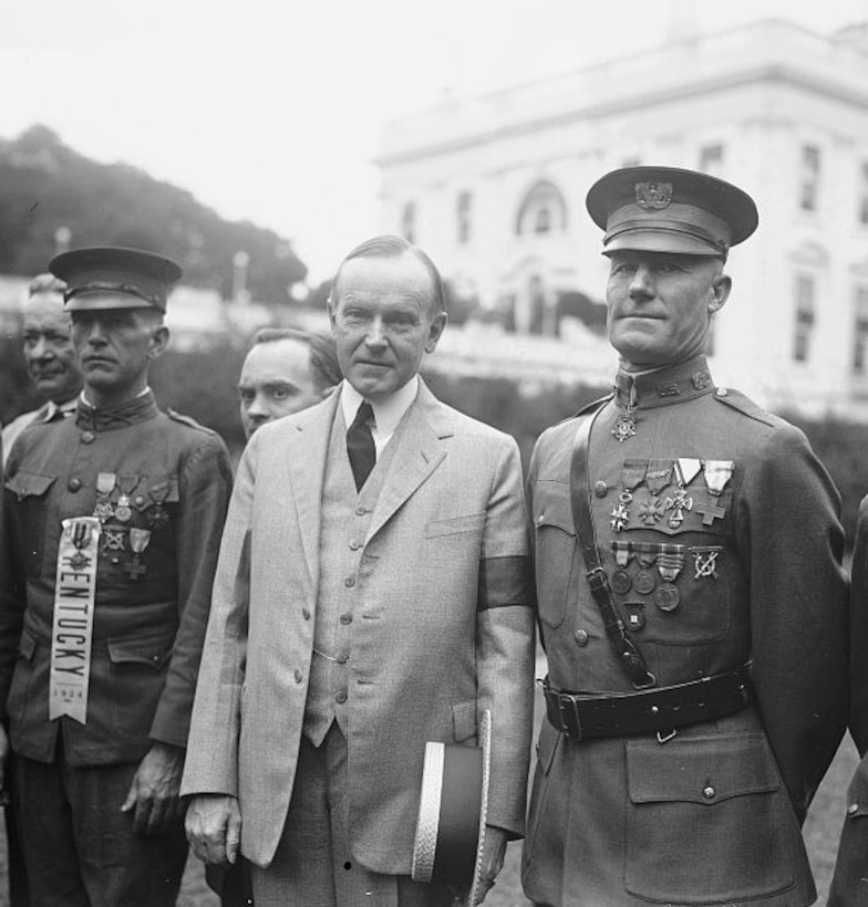 Two soldiers stand beside another man outside.