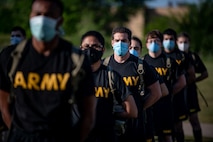 Soldiers stand in formation in masks wearing their black and gold Army t-shirts and backpacks.