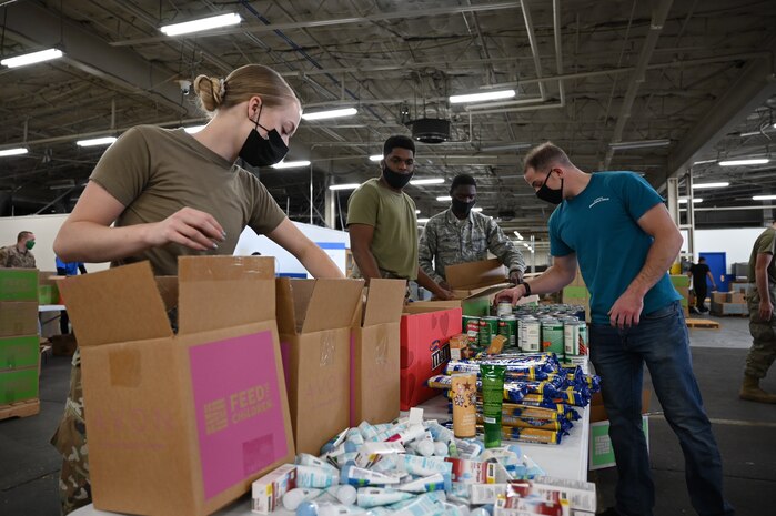 Volunteers along with local community members assemble boxes of food and personal care items.