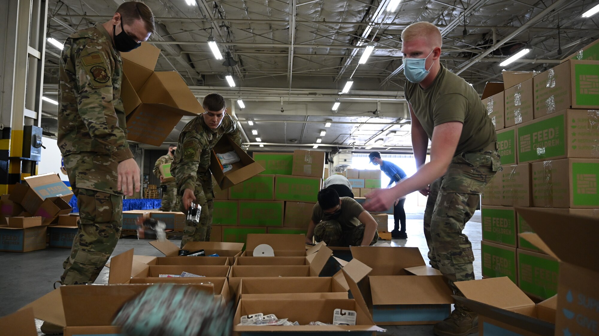 Volunteers along with local community members assemble boxes of food and personal care items.