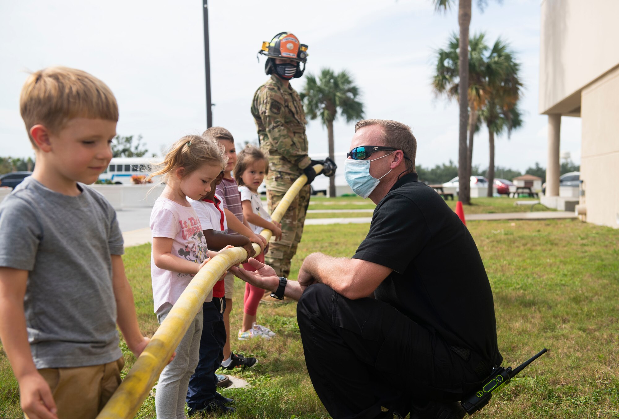 man shows fire hose to children