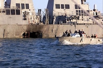 Archive photo from Oct. 18, 2000, re-released. U.S. Navy and Marine Corps security personnel patrol pass the damaged U.S. Navy destroyer USS Cole (DDG 67) following the Oct. 12, 2000 terrorist bombing attack on the ship in Aden, Yemen.