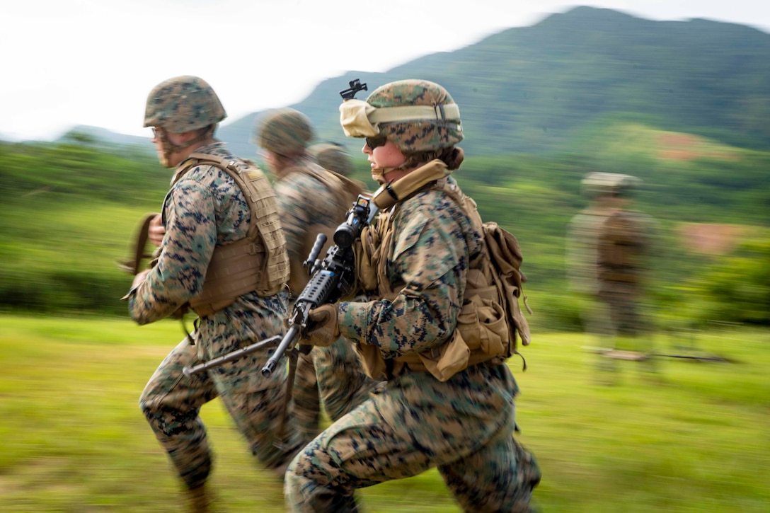 Marines run together while holding their weapons.