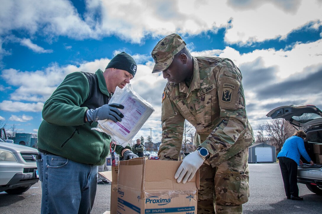 Two people organize a box of personal protective equipment