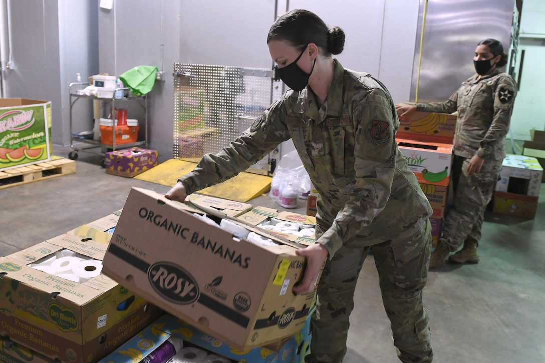 An airman stacks boxes of food.
