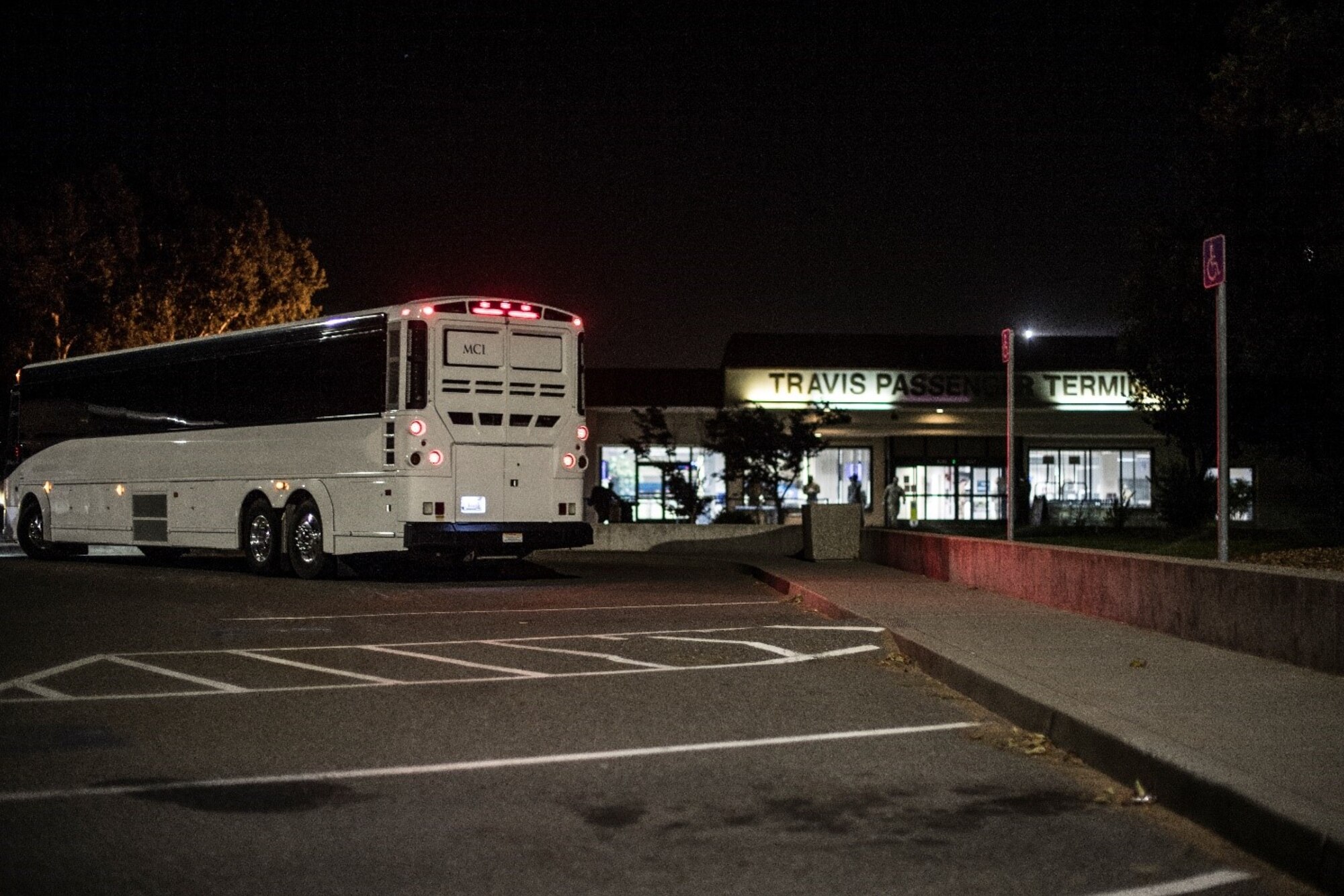 A bus pulls up to a building akin to an airport at night.