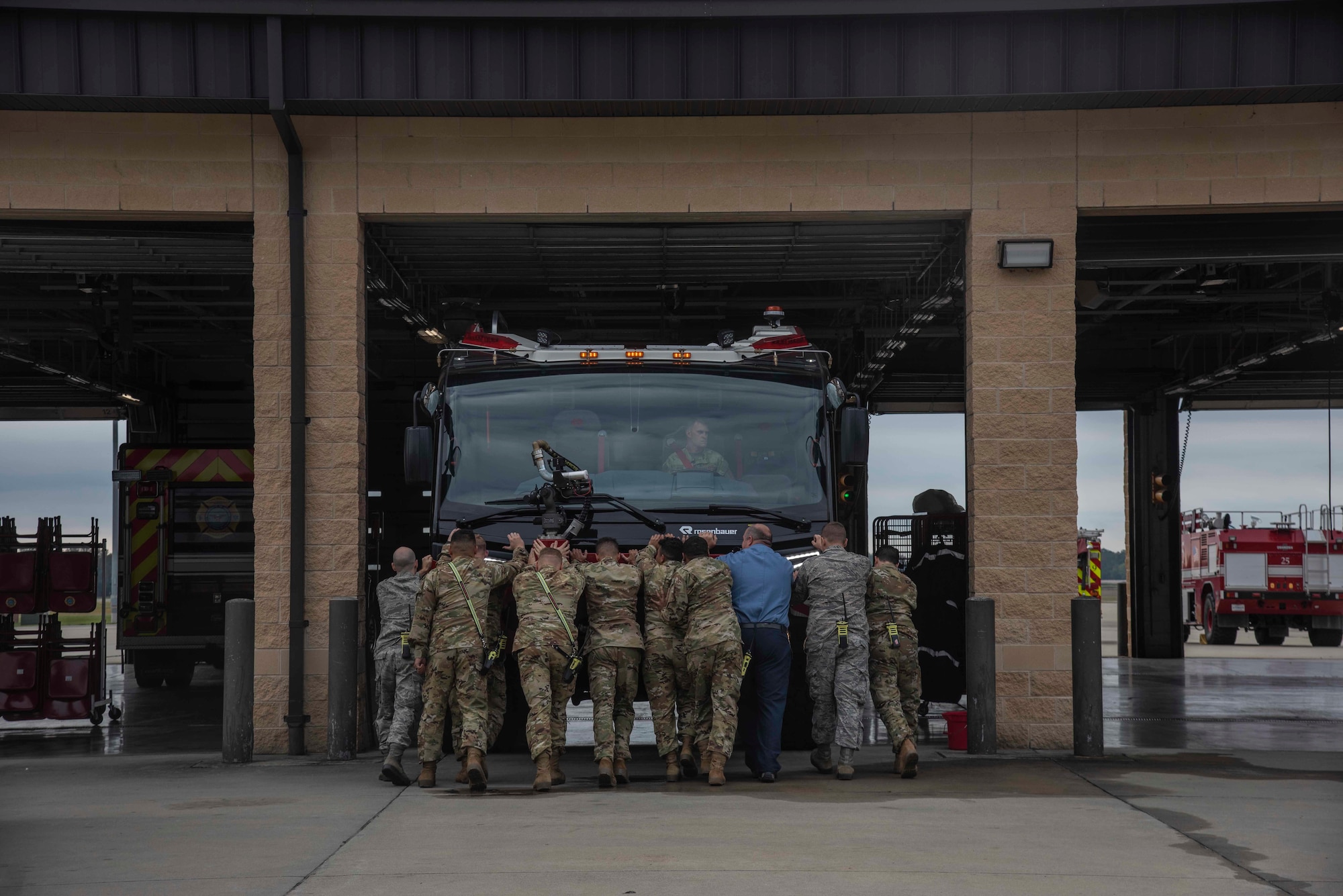 Airmen from the 4th Civil Engineer Squadron fire department push the new firetruck into the garage at Seymour Johnson Air Force Base, N.C., Oct. 9, 2020. During the ceremonial exchange of fire trucks, a new truck replaces an old one and the new one is pushed into the garage by the firemen. (U.S. Air Force photo by Senior Airman Kylee Gardner)