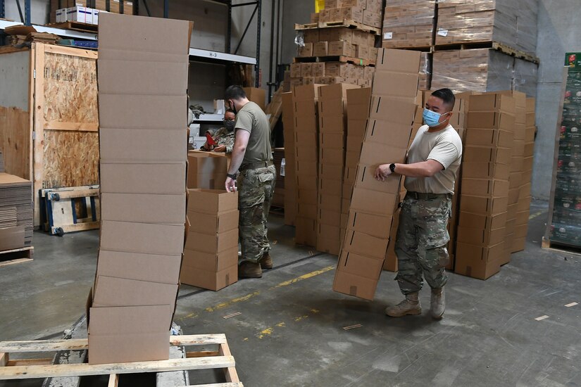 Airmen wearing masks carrying boxes.