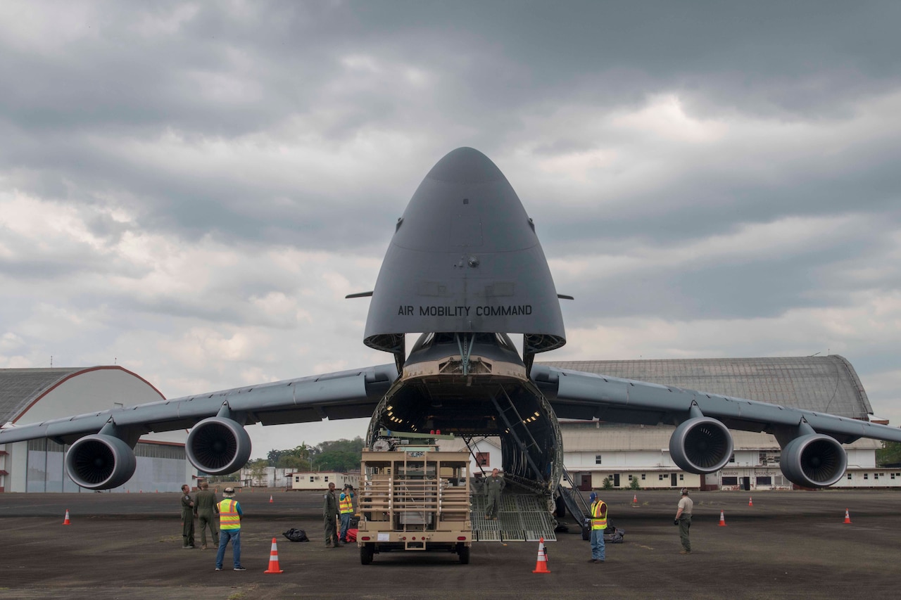 Airmen load cargo into a huge aircraft.
