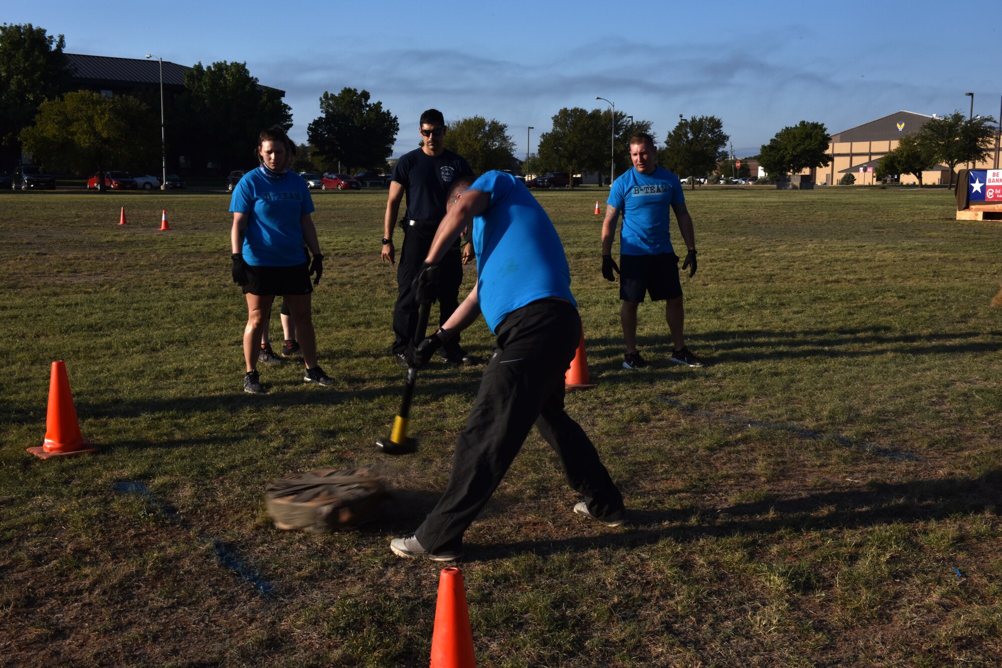 Team members cheer on a teammate using a sledge hammer to move a rolled hose across the field during the 15th Annual Fire Muster Challenge at the Goodfellow Fire Department on Goodfellow Air Force Base, Texas, Oct. 9, 2020. Contestants had to move the rolled hose by only hitting it with the sledge hammer before moving to the next obstacle. (U.S. Air Force photo by Staff Sgt. Seraiah Wolf)