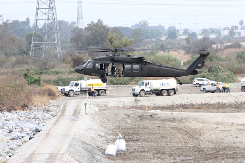 A California Army National Guard UH-60 Black Hawk places a 3,000-pound sandbag at the Whittier Narrows Dam Basin in Montebello, California, as part of an exercise during which the district teamed up with the California Army National Guard to demonstrate flood-mitigation capabilities.