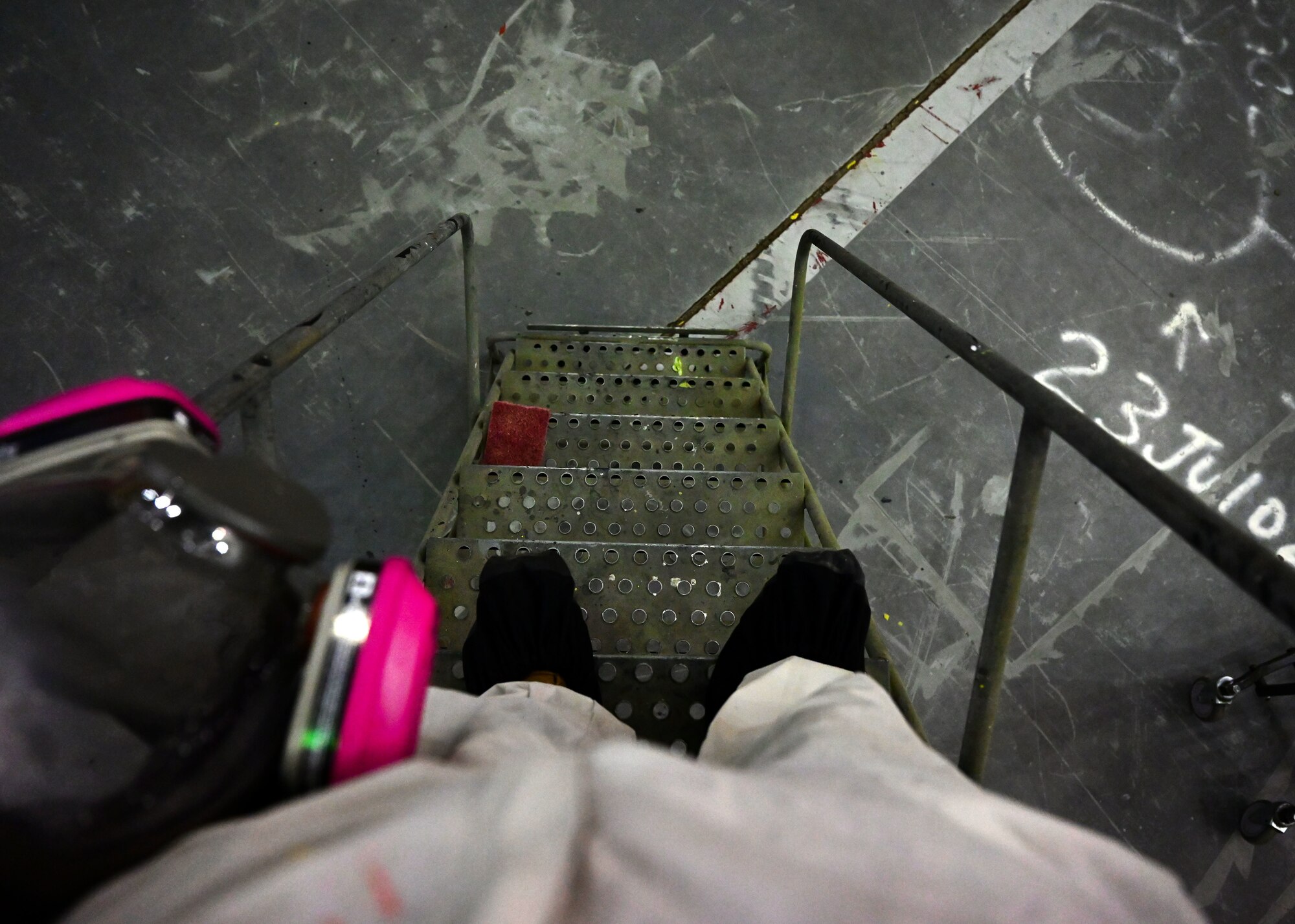 An Airman in a white suit walks down a set of stairs.