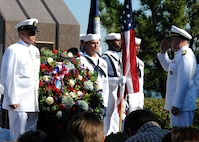 Adm. J. C. Harvey Jr., right, commander of U.S. Fleet Forces Command, salutes as Master Chief Steven Timmons, left, and Seaman Dingji Zhuang, both assigned to the guided-missile destroyer USS Cole, present a wreath at the USS Cole memorial at Naval Station Norfolk during the 10th anniversary remembrance ceremony of the terrorist attack on Cole.