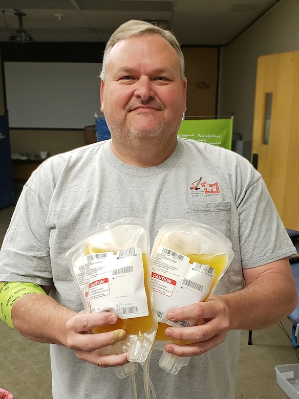 A man holds two bags containing a yellowish liquid.