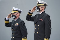 Cmdr. Edward Pledger, commander, USS Cole (DDG 67) and Lt. j.g. Harry Hazell, Chaplin, USS Cole, salutes during the National Anthem at the Arleigh Burke-class guided missile destroyer USS Cole (DDG 67) 20th Anniversary memorial ceremony at Naval Station Norfolk.