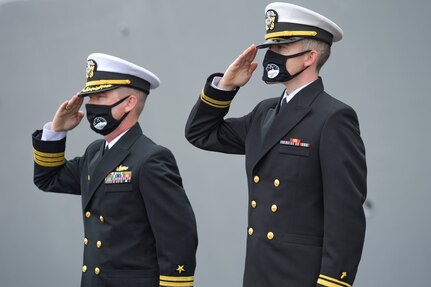 Cmdr. Edward Pledger, commander, USS Cole (DDG 67) and Lt. j.g. Harry Hazell, Chaplin, USS Cole, salutes during the National Anthem at the Arleigh Burke-class guided missile destroyer USS Cole (DDG 67) 20th Anniversary memorial ceremony at Naval Station Norfolk.