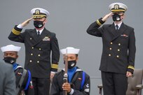 Cmdr. Edward Pledger, commander, USS Cole (DDG 67) and Lt. j.g. Harry Hazell, Chaplin, USS Cole, salutes during the National Anthem at the Arleigh Burke-class guided missile destroyer USS Cole (DDG 67) 20th Anniversary memorial ceremony at Naval Station Norfolk.