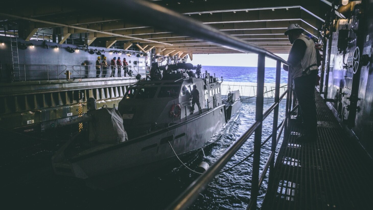 U.S. Sailor assigned to amphibious dock landing ship USS Comstock (LSD 45), observes a Patrol Boat (PB) Mk VI assigned to Maritime Expeditionary Security Squadron 3 during green well operations, Oct. 4, 2020. Maritime Expeditionary Security Force and Explosive Ordnance Disposal Mobile Unit Sailors assigned to Commander, Task Force 75 (CTF 75) embarked and are conducting integrated littoral maritime security operations from the amphibious dock landing ship USS Comstock (LSD 45) with the Marines and Sailors already deployed as Task Force Ellis from I Marine Expeditionary Force. PB Mk VI provides increased capabilities to amphibious warships and can operate directly in support of the Navy platform or independently in support of mission tasking. (U.S. Marine Corps photo by Sgt. Manuel A. Serrano)
