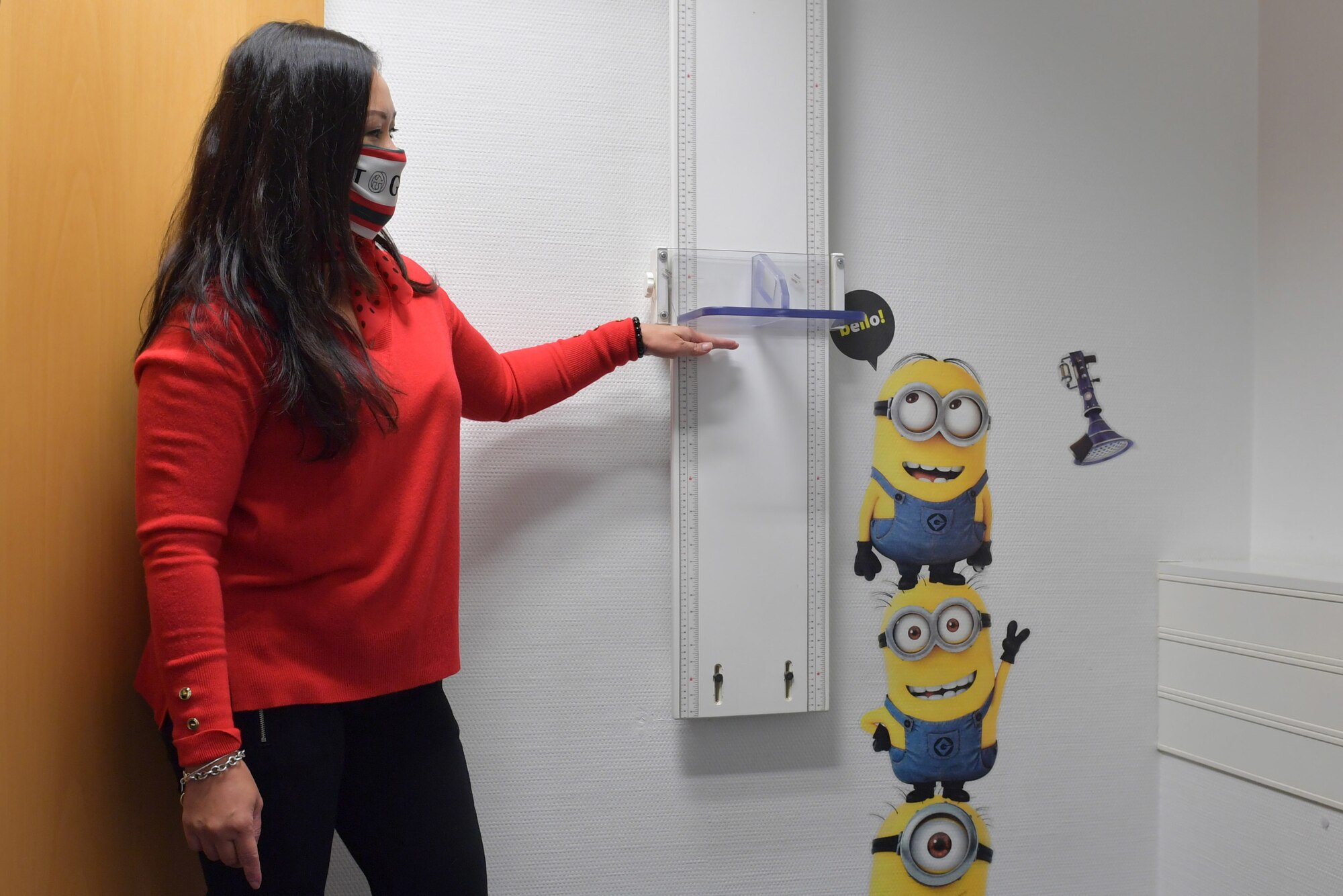 A woman standing next to a height measurement ruler.