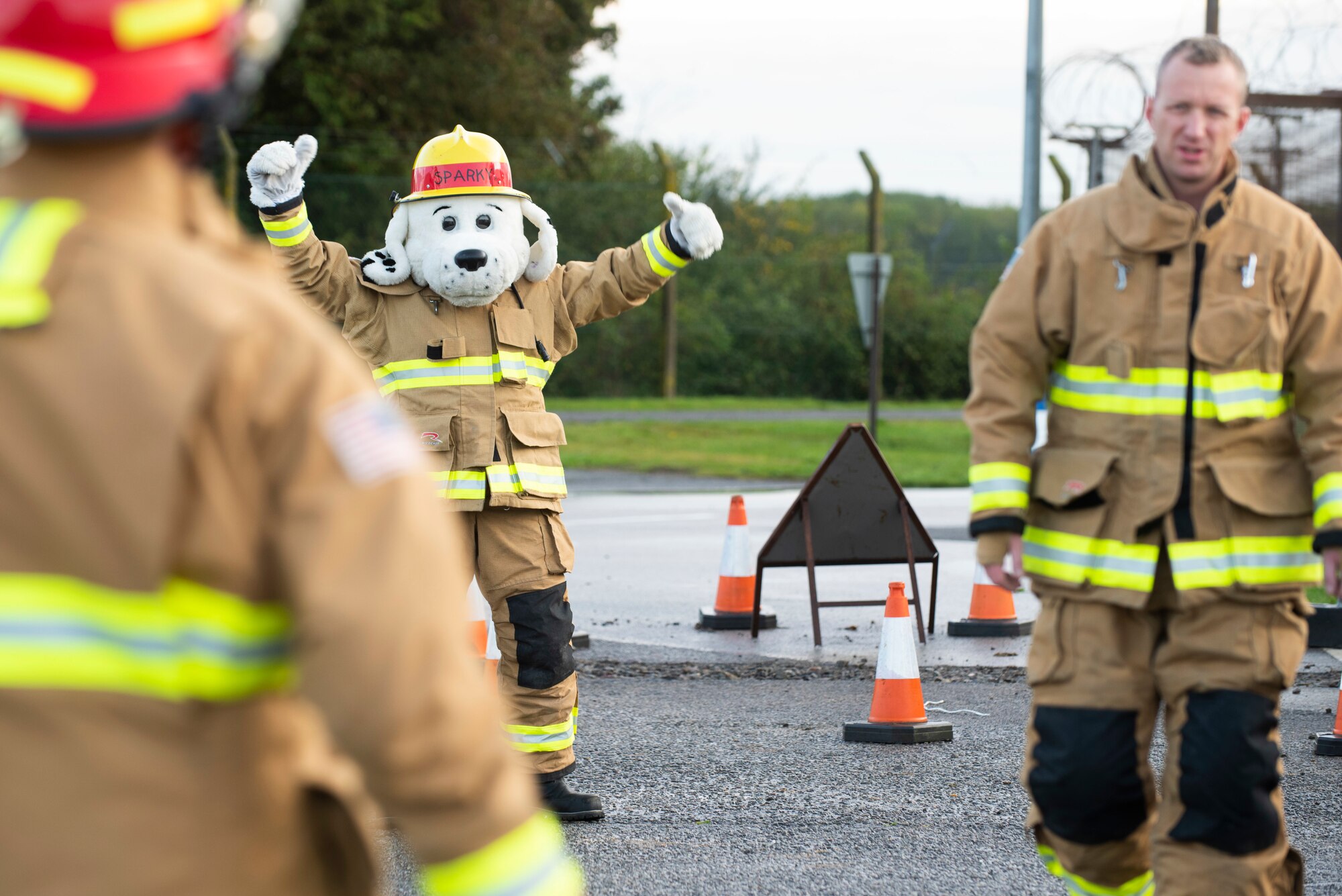 Sparky the Fire Dog and 423rd Civil Engineer Squadron firefighters welcome drivers to RAF Molesworth, England, Oct. 6, 2020 during Fire Prevention Week 2020. Sparky was created for the National Fire Protection Association in 1951 to teach children and adults about fire safety. (U.S. Air Force photo by Senior Airman Jennifer Zima)