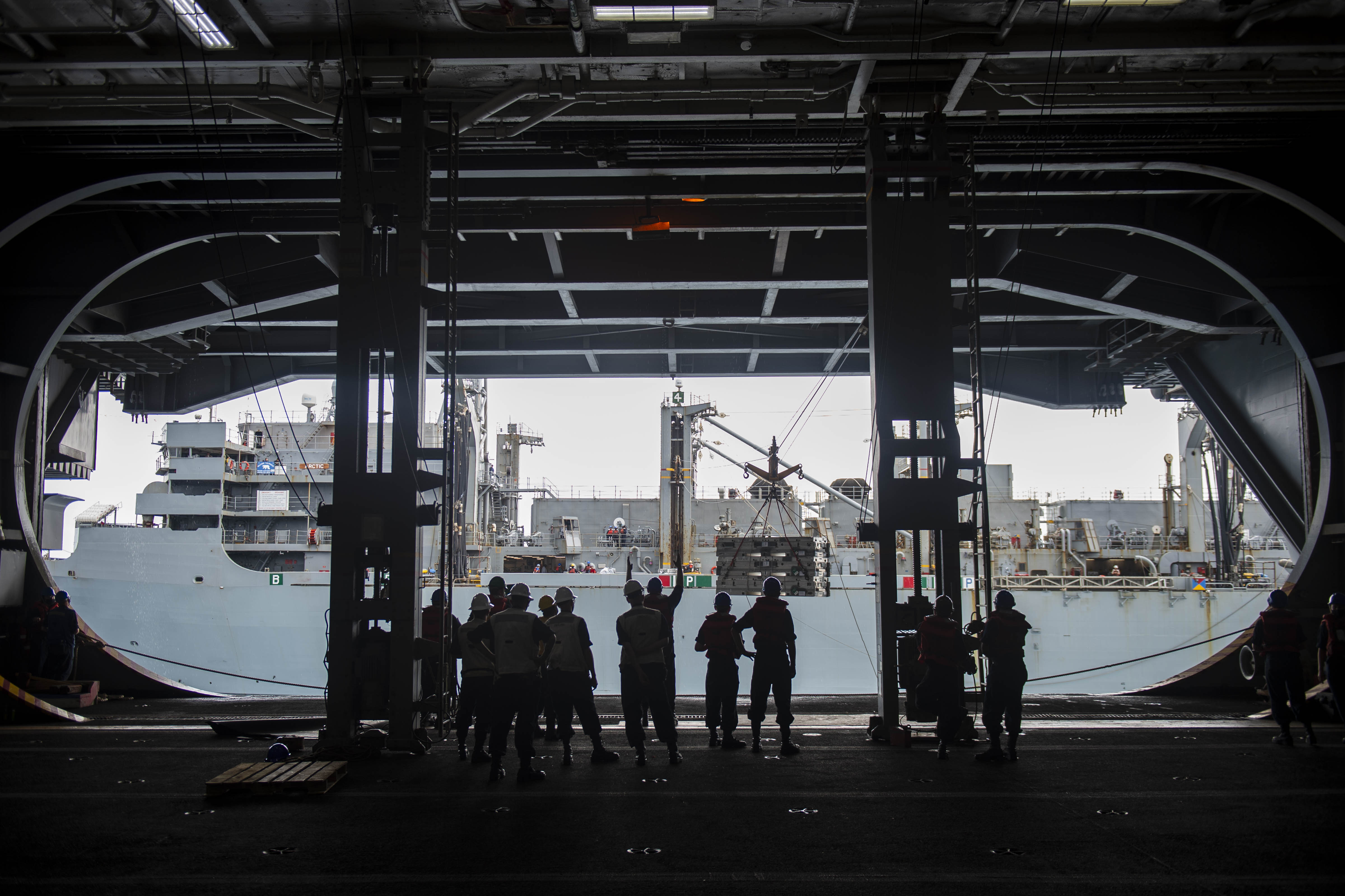 Sailors aboard the Nimitz-class aircraft carrier USS Dwight D. Eisenhower (CVN 69) receive ordnance from the fast combat support ship USNS Arctic (T-AOE 8) during a replenishment-at-sea.