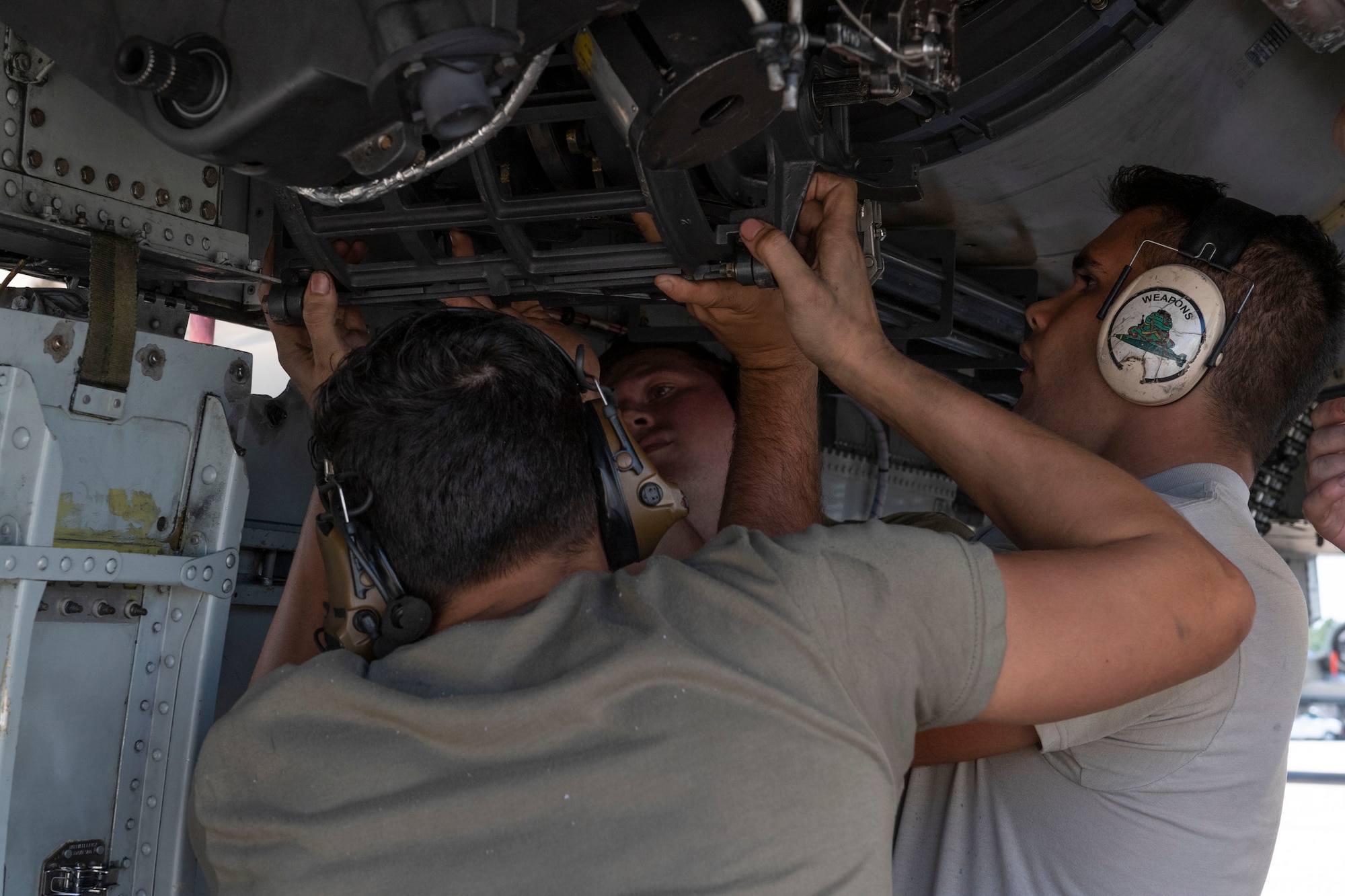 A photo of Airmen  install a GAU-8 Avenger 30 mm cannon ammunition element on an A-10C Thunderbolt II.