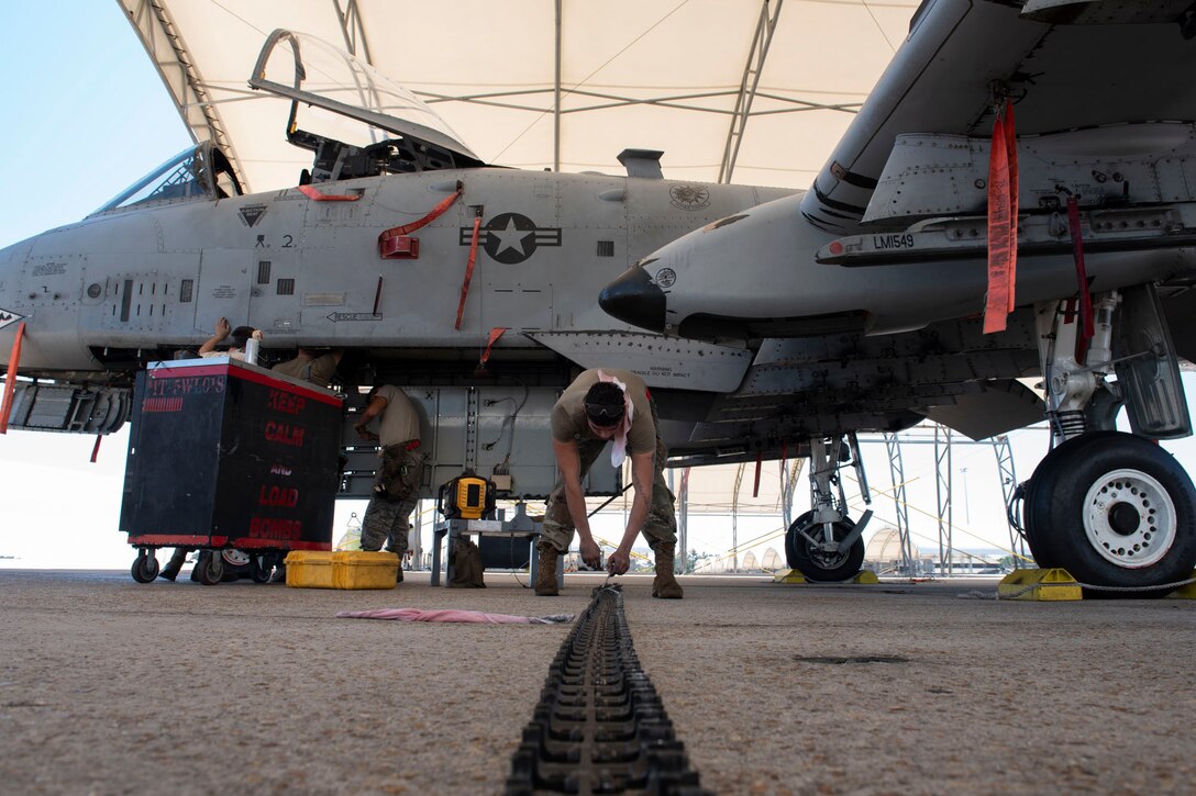 A photo of an Airman counting conveyor elements before they are loaded into the GAU-8 Avenger 30 mm cannon on an A-10C Thunderbolt II.