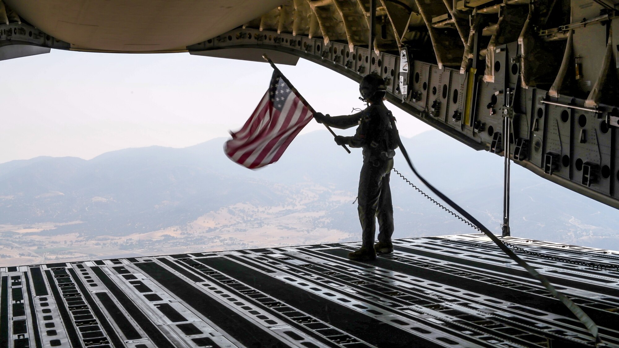Staff Sgt. Kori Myers, 418th Flight Test Squadron C-17 load master, waves the U.S. flag from the back of a C-17 Globemaster III during the 2020 Aerospace Valley Air Show at Edwards Air Force Base, Oct. 9. (Air Force photo by Giancarlo Casem)
