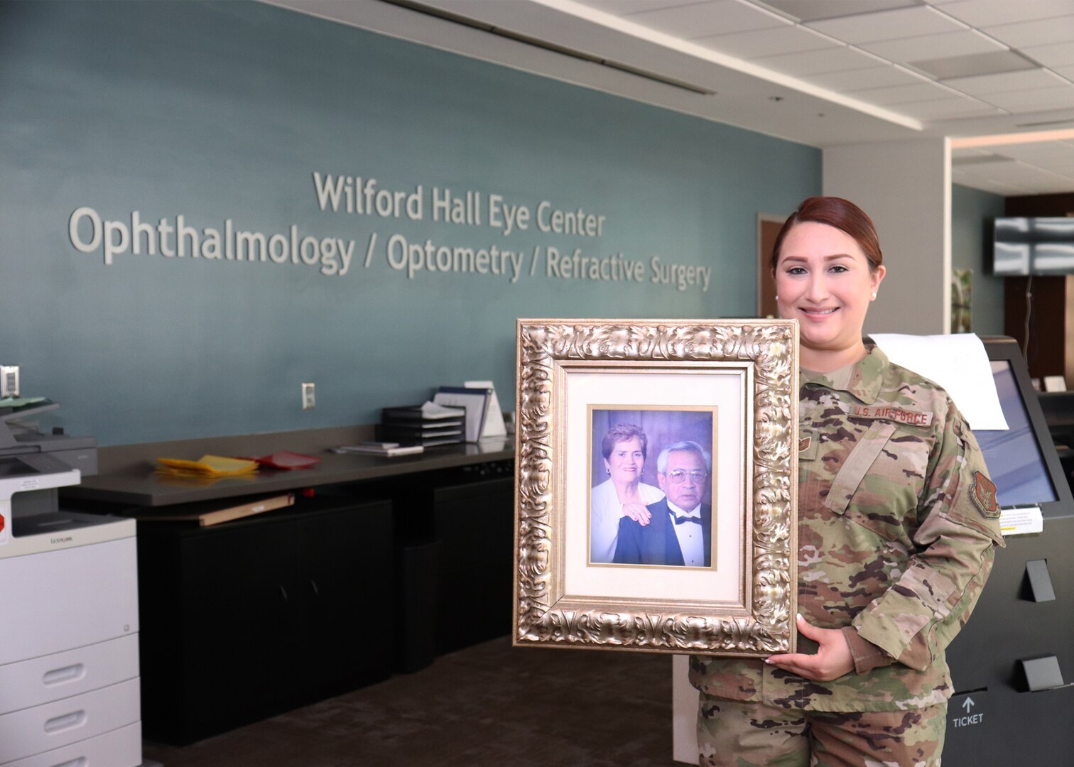 Tech. Sgt. Christine R. Narro, 433rd Aerospace Medicine Squadron, an enlisted Reserve Citizen Airman with the 433rd Airlift Wing at Joint Base San Antonio–Lackland, Texas, holds a picture frame of her grandfather, Felix Gonzalez and grandmother, Josefina, in the lobby of Wilford Hall Eye Center. This is the location where she works as an Optometry Technician during her Unit Training Assemblies on her weekend duty.  (U.S. Air Force photo by Tech. Sgt. Iram Carmona)