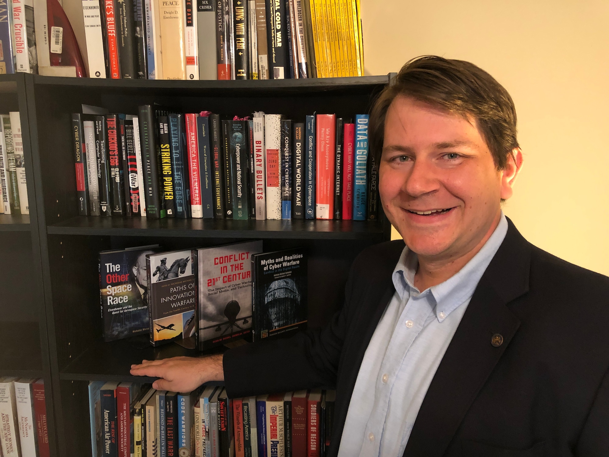 Dr. Nicholas Sambaluk, Air Command and Staff College associate professor of strategy and director of research at the eSchool of Graduate Professional Military Education, poses near a book case.