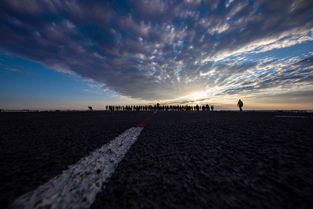 Sailors walk across the deck of a ship.