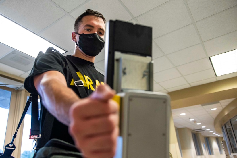 A soldier holds his wrist up to a scanner to be scanned.