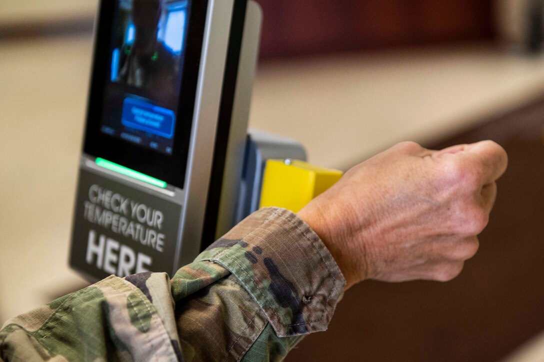 A soldier holds their wrist up to a scanner to be scanned.
