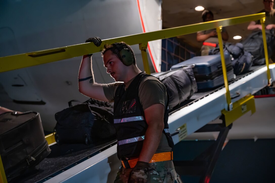 An Airmen helps load luggage onto the plane.