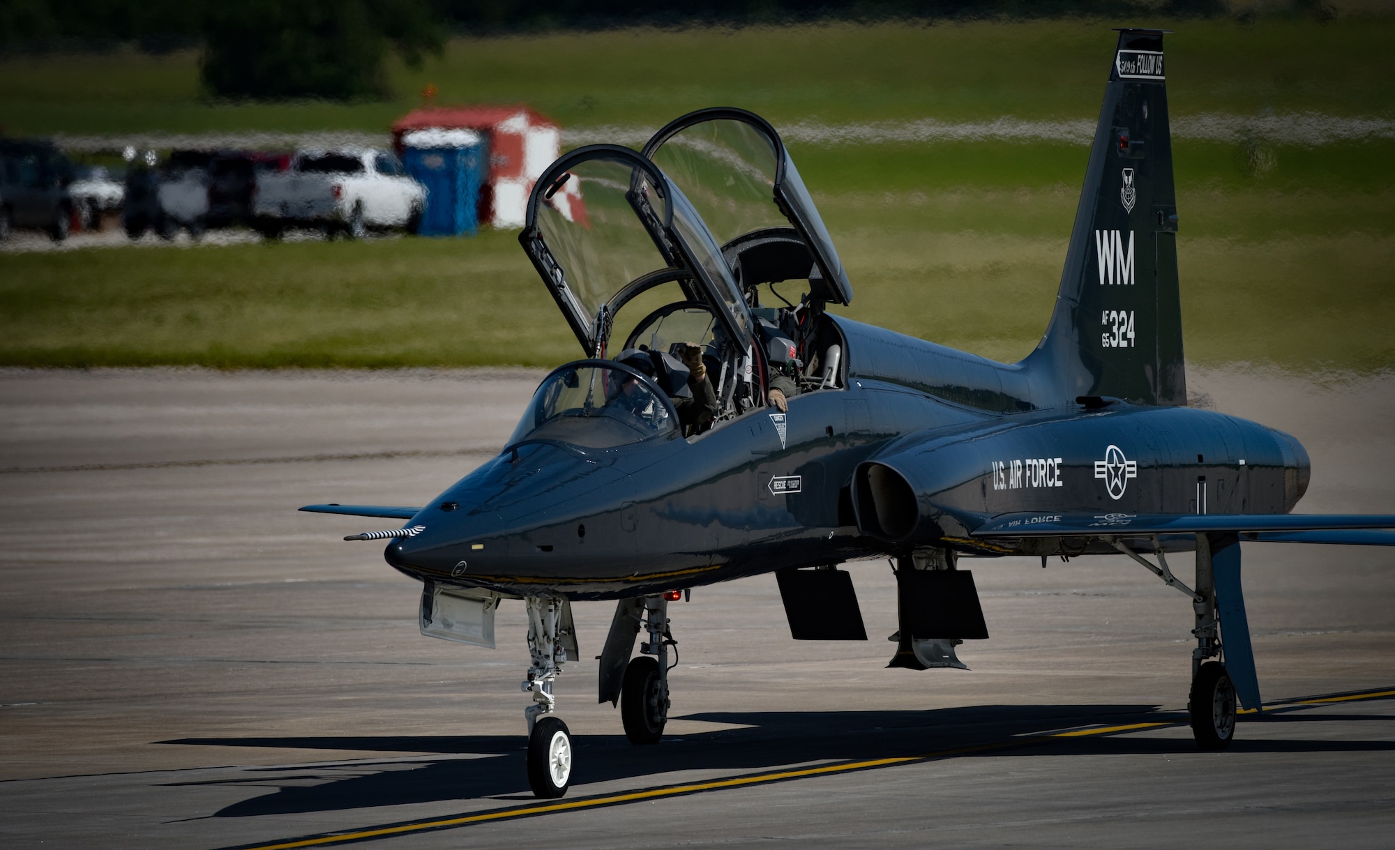A T-38 Talon pilot assigned to the 13th Bomb Squadron waves to air show spectators as he taxis his aircraft in front of the crowed during the 2019 Wings over Whiteman Air & Space Show at Whiteman Air Force Base, Missouri, June 15, 2019. The T-38 is a crucial asset utilized to maintain airmanship and tactics for B-2 pilots. B-2 pilots assigned to the 13th Bomb Squadron demonstrated their jet flying skills for more than 100,000 visitors during the air show weekend. (U.S. Air Force photo by Tech. Sgt. Alexander W. Riedel)