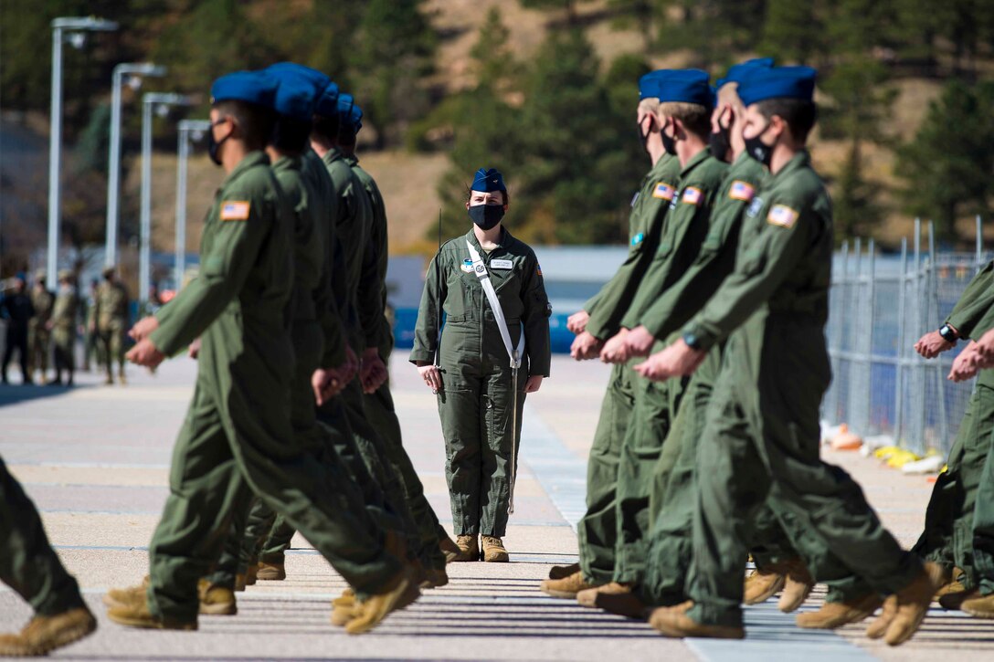 Air Force cadets walk in formation as another cadet watches.