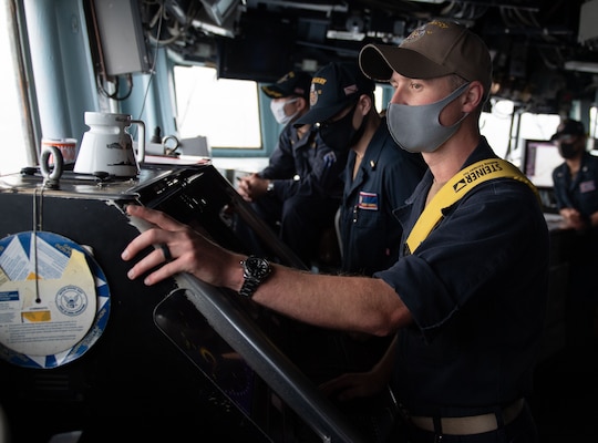 Lt. j.g. Benjamin Pershall scans the horizon while standing watch aboard the Arleigh-Burke class guided missile destroyer USS Barry (DDG 52) during routine operations in the Indo-Pacific region.