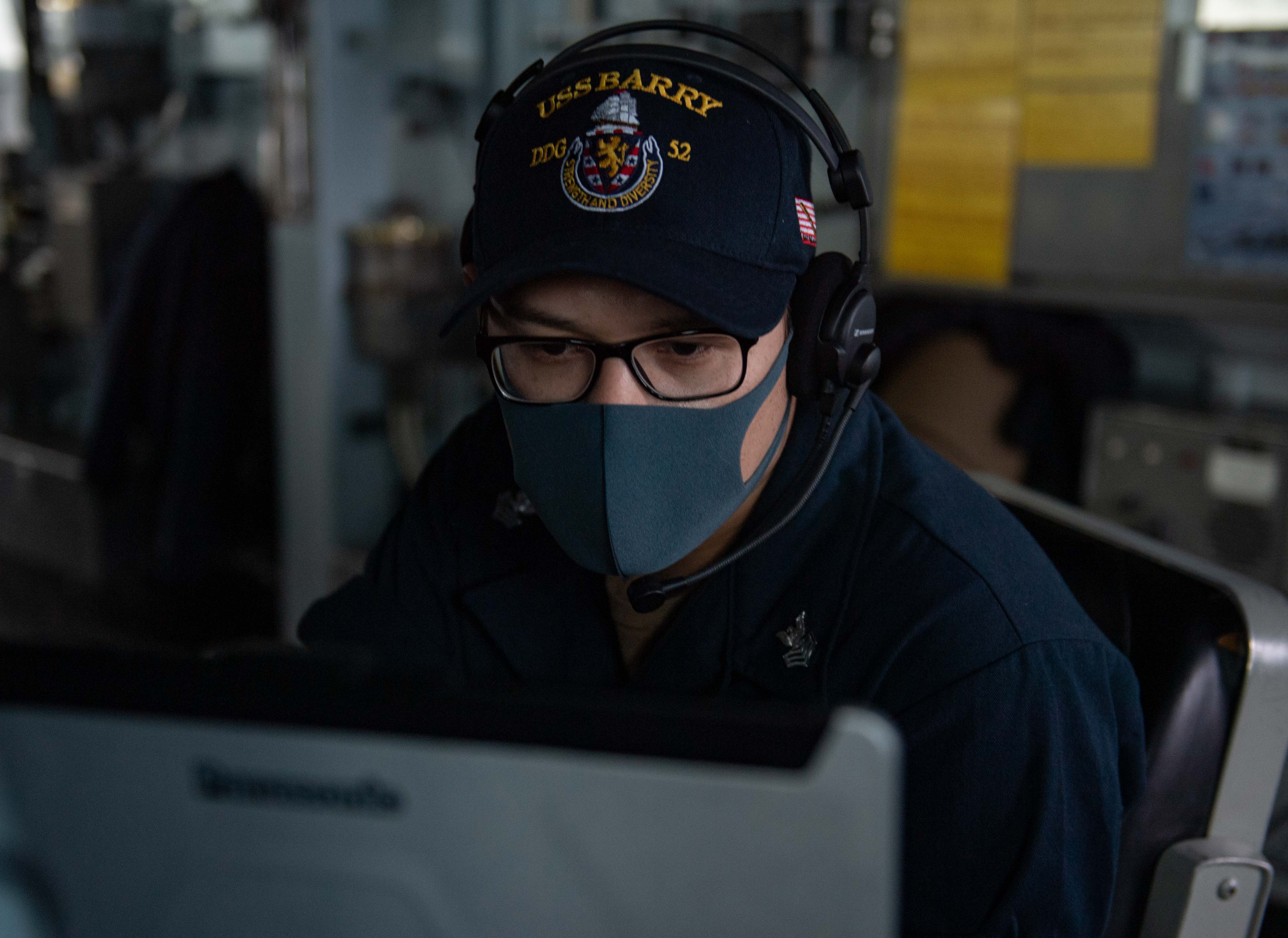 Operations Specialist 1st Class Jose Gonzalez looks for contacts on the Automated Information System (AIS) laptop while standing watch aboard the Arleigh-Burke class guided missile destroyer USS Barry (DDG 52).