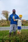 U.S. Air Force Col. Jesse J. Friedel, 35th Fighter Wing commander, holds up stalks of rice while standing next to a scarecrow during a community relations event in Misawa City, Japan, Oct. 8, 2020. Friedel and his family joined Misawa Mayor Yoshinori Kohiyama and Oozora Elementary School students to harvest rice, the primary staple of the Japanese diet. (U.S. Air Force photo by Tech. Sgt. Timothy Moore)