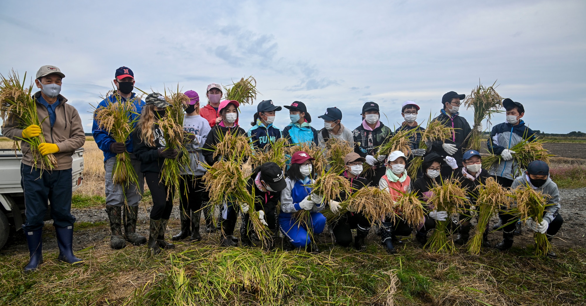 Misawa Mayor Yoshinori Kohiyama, far left, and U.S. Air Force Col. Jesse J. Friedel, 35th Fighter Wing commander, pose for a photo with Friedel's family and Oozora Elementary School students during a rice harvesting event in Misawa City, Japan, Oct. 8, 2020. Rice is the primary staple food of the Japanese diet and of such fundamental importance to the Japanese culture that it was once used as currency. (U.S. Air Force photo by Tech. Sgt. Timothy Moore)