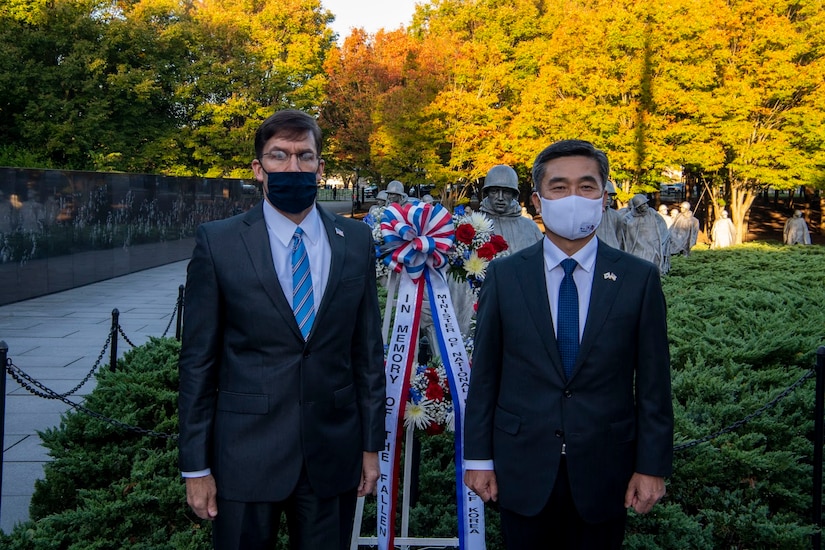 Men stand beside a wreath.