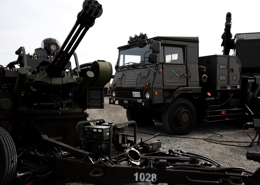 Two large green pieces of equipment sit on a pavement outside