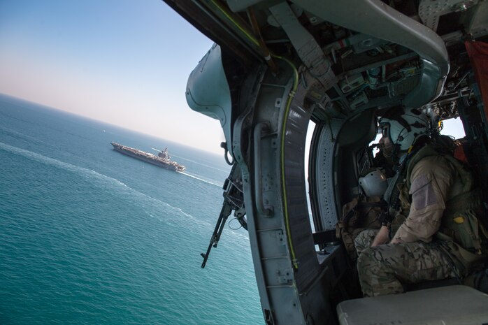 Naval Aircrewman (Helicopter) 2nd Class Steve Reynolds, assigned to Helicopter Sea Combat Squadron (HSC) 26, watches from an MH-60S Sea Hawk helicopter as the aircraft carrier USS Nimitz (CVN 68) sails in the Arabian Gulf, Oct. 11. HSC-26 and the Nimitz Carrier Strike Group are deployed to the U.S. 5th Fleet area of operations in support of naval operations to ensure maritime stability and security in the Central Region, connecting the Mediterranean and Pacific through the Western Indian Ocean and three critical chokepoints to the free flow of global commerce.